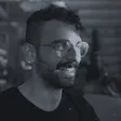 Alejandro Tlaie Boria, smiling, wearing glasses and a black T-shirt